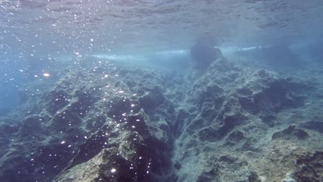 fondo marino rocoso submarino y burbujas formadas en las aguas azules de paralia emplisi, grecia