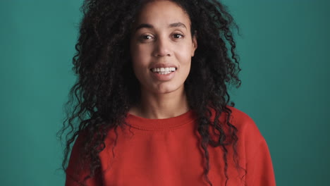 una mujer afroamericana sonriente sobre un fondo azul.