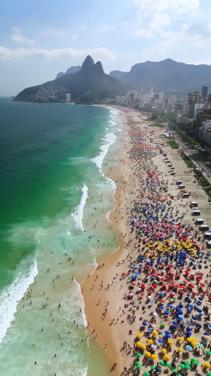 Vertical aerial descent over Ipanema Beach with Dois Irmãos peaks and city skyline