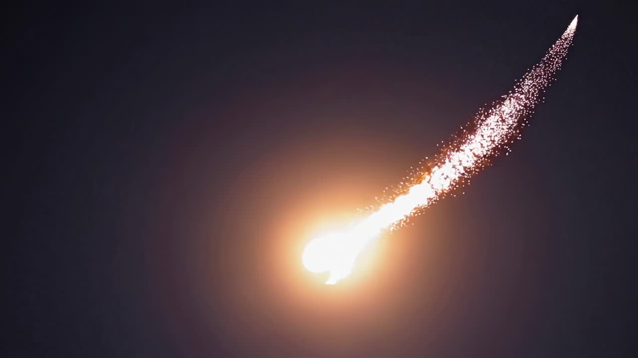 Ein dramatisches Videostandbild einer in der Luft explodierenden Rakete vor dunklem Himmel, aus niedriger Perspektive aufgenommen
