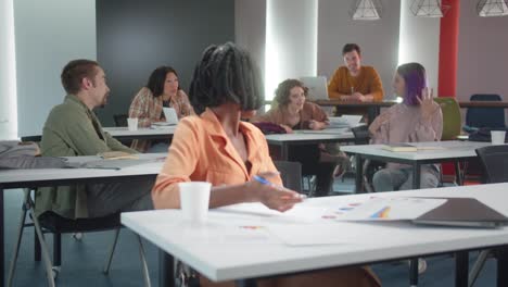 una atractiva joven profesora africana se está preparando para el seminario, hablando con sus estudiantes y están sonriendo juntos