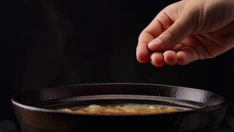 adding seasoning to a steaming pot of food