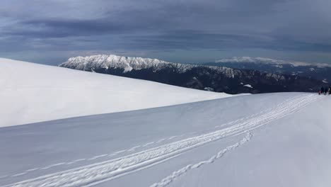 Snowy-mountain-ridge-with-Piatra-Craiului-in-the-distance,-Iezer-Papusa,-Arges,-Romania,-under-a-clear-sky