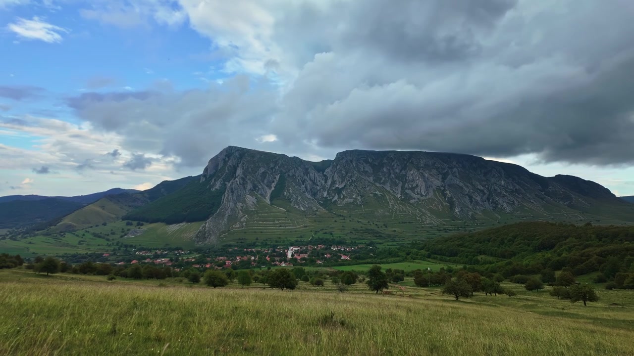 Pueblo de Rimetea bajo Piatra Secuiului en los Montes Trascău, Transilvania, con prados otoñales, formaciones de nubes y vistas panorámicas del valle en timelapse.