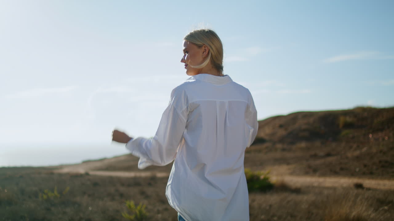 Blondes Mädchen geht auf ein Schloss zu, Rückansicht. Ruhige Frau geht allein durch Sommerlandschaft.