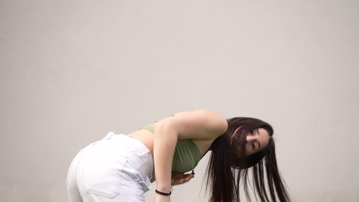 Donna con top verde e pantaloni bianchi che balla