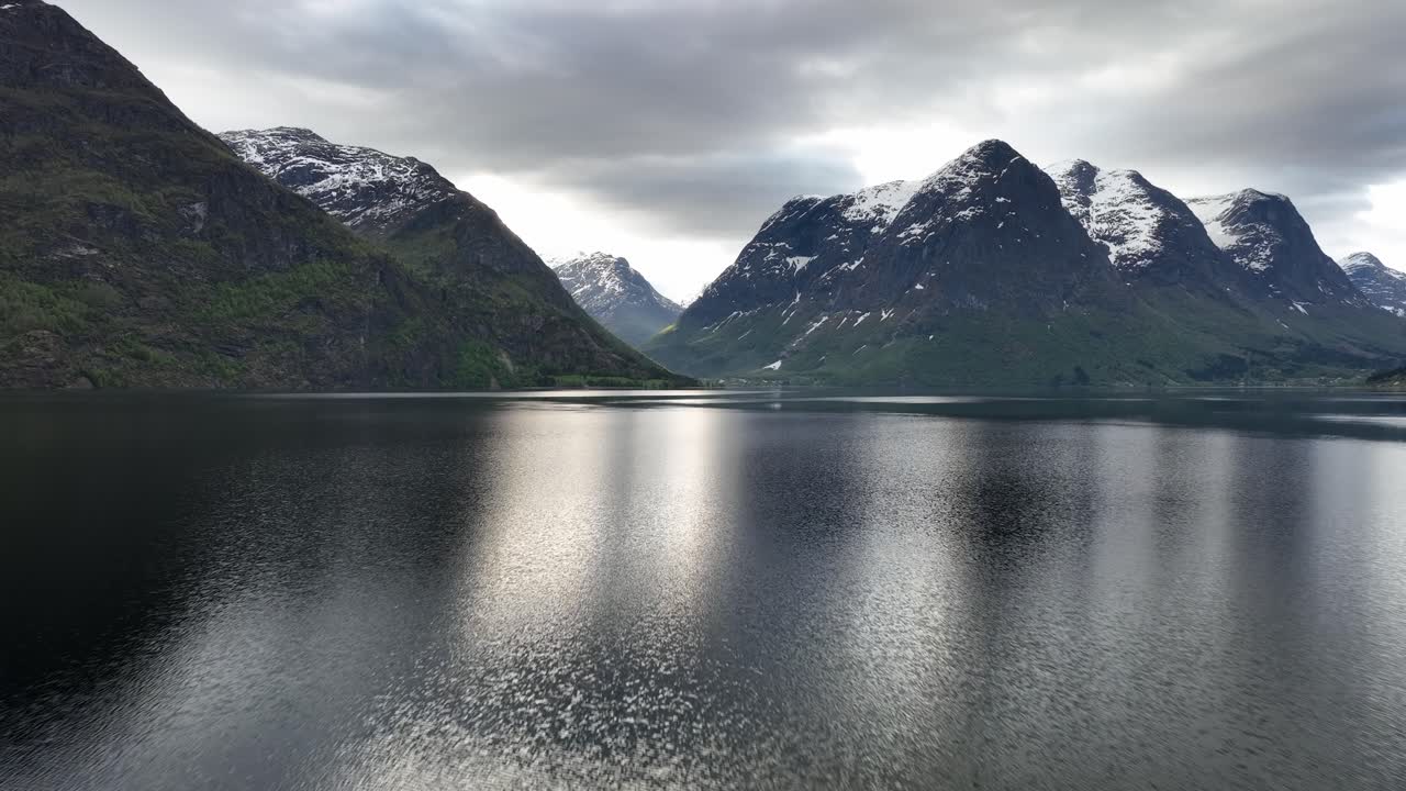Hjelledalen sedd från sjön Oppstrynsvatnet i Norge - Morgonflygbild som flyger framåt nära vattenytan.
