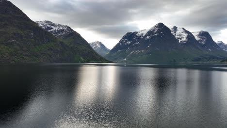 el valle de hjelledalen visto desde el lago oppstrynsvatnet en noruega - vuelo aéreo matutino hacia adelante cerca de la superficie del agua