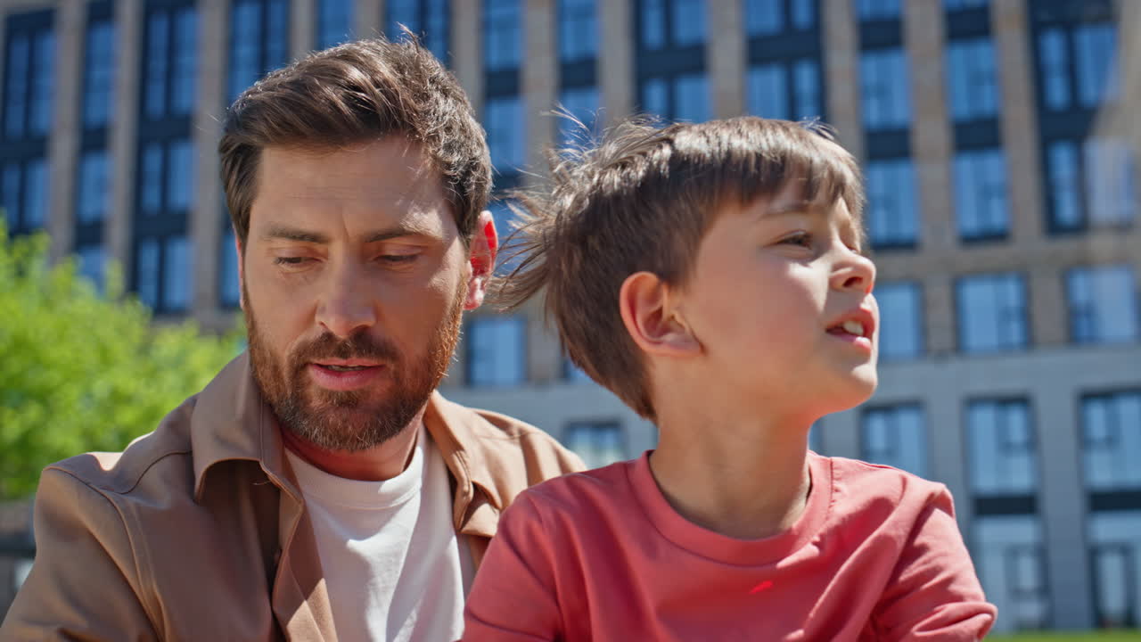 Closeup father son talking at nature. Man speaking to child enjoying picnic