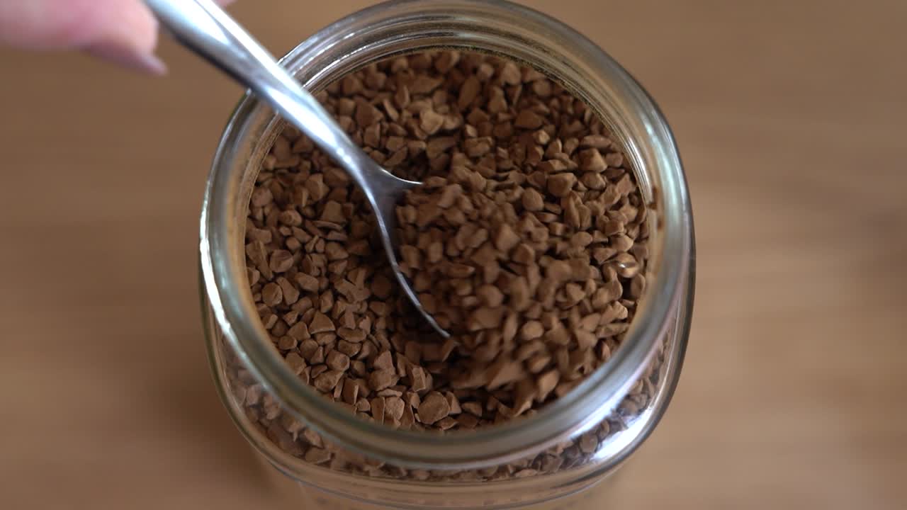 Close-up of scooping instant coffee from the jar and into a mug.