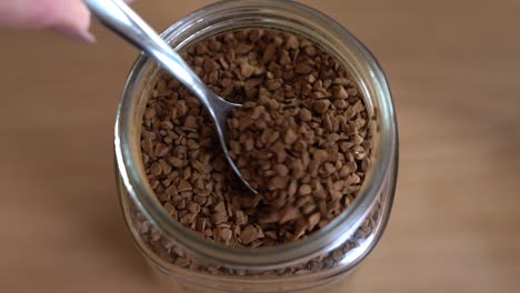 close-up of scooping instant coffee from the jar and into a mug.
