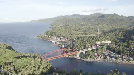 Mit-Blick-Auf-Das-Blaue-Wasser,-Umgeben-Von-Bewaldeten-Bergen-Unter-Der-Goldenen-Metallbrücke-Mit-Fahrzeugen,-Die-In-Der-Nähe-Des-Kleinen-Fischerdorfs-In-Der-Provinz-Leyte,-Philippinen,-Fahren