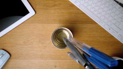 Pens-falling-and-landing-in-glass-on-office-desk