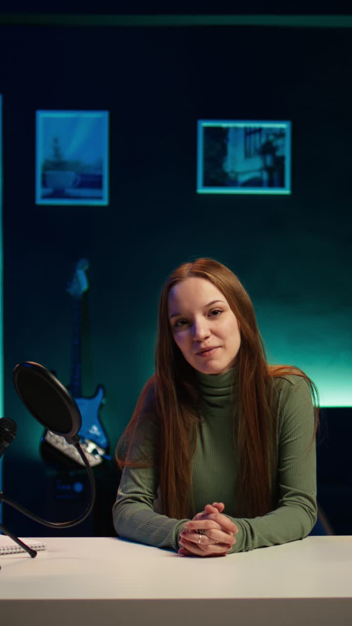 Giovane donna seduta alla scrivania nel suo studio domestico che parla alla fotocamera