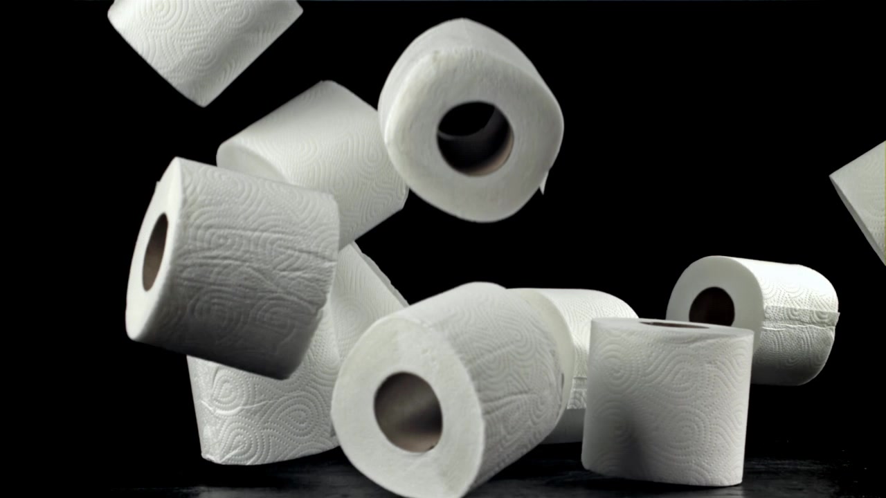 Multiple Toilet Paper Rolls Falling in Slow Motion on Black Background