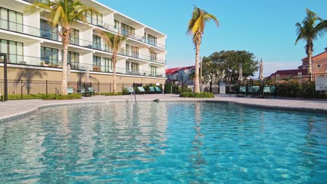 A-close-up-drone-shot-of-the-pool-water-with-loungers,-and-tables-with-umbrellas-near-by-in-Melbourne-Florida