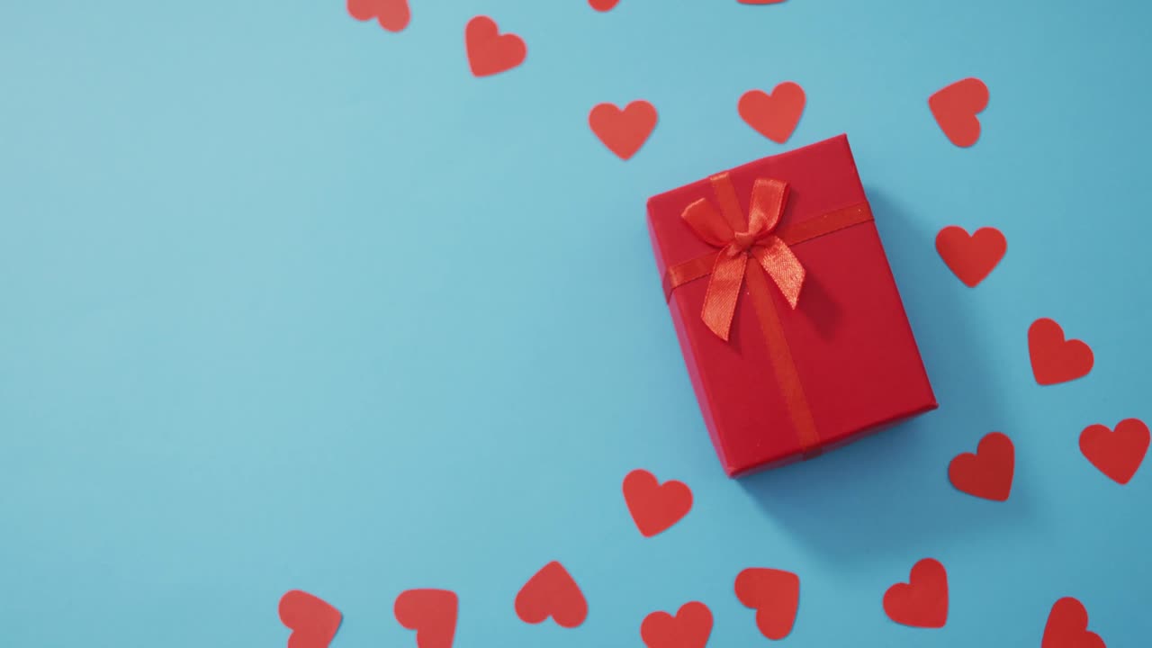 Multiple red paper hearts and red present at valentine's day on blue background