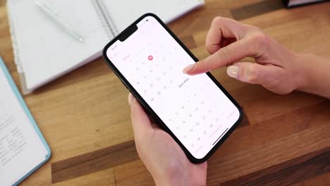 woman's hands using a calendar app on a smartphone