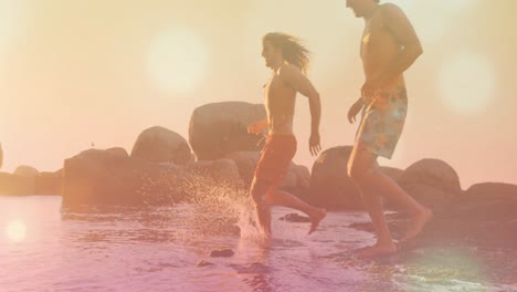 Animation-of-glowing-spots-over-caucasian-men-running-at-beach