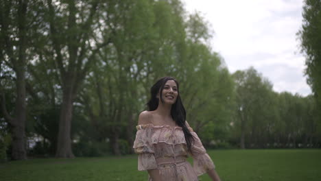 gorgeous and playful hispanic brunette modeling and waving goodbye, smiling with a floral dress