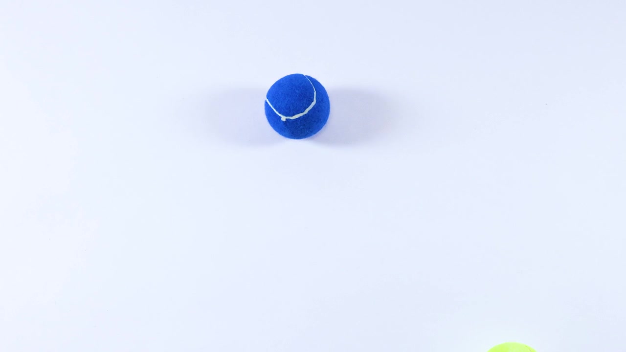 Various colored tennis balls bouncing on white surface