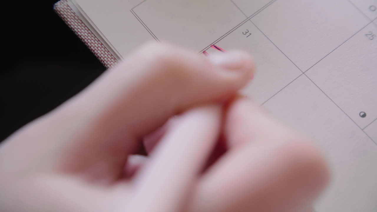 특정 시간 4k에 대한 목표를 설정하는 동안 그녀의 달력 노트북 메모에 끝을 쓰는 젊은 여성