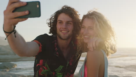 beautiful couple taking selfie at sunset using phone