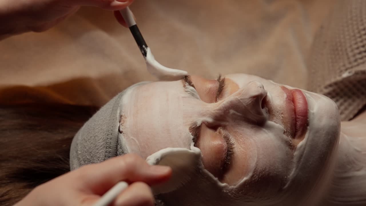 Estetista che applica una maschera viso sul volto di una donna in una spa