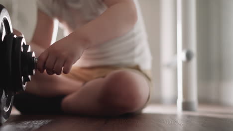 curious little boy plays with heavy barbell for workout