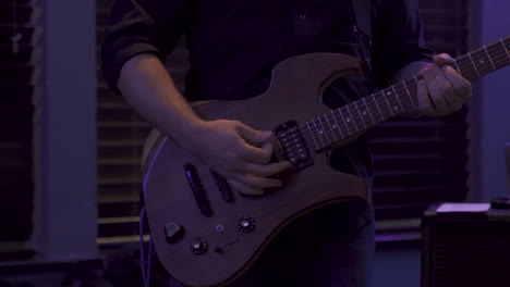 distant shot of man playing music on a guitar in a low light venue in 4k