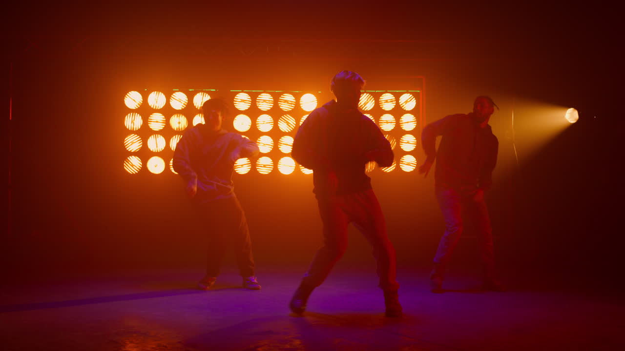 Fajni chłopcy tańczący hip-hop w migających światłach w tle. Tancerze występujący na scenie.