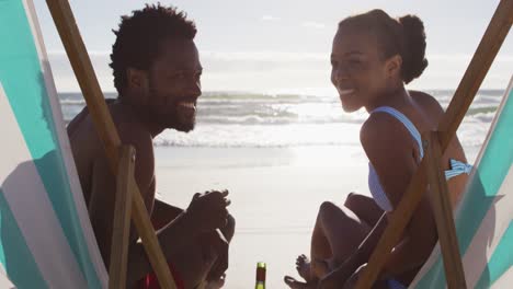Porträt-Eines-Afroamerikanischen-Paares,-Das-Lächelt-Und-In-Liegestühlen-Am-Strand-Sitzt