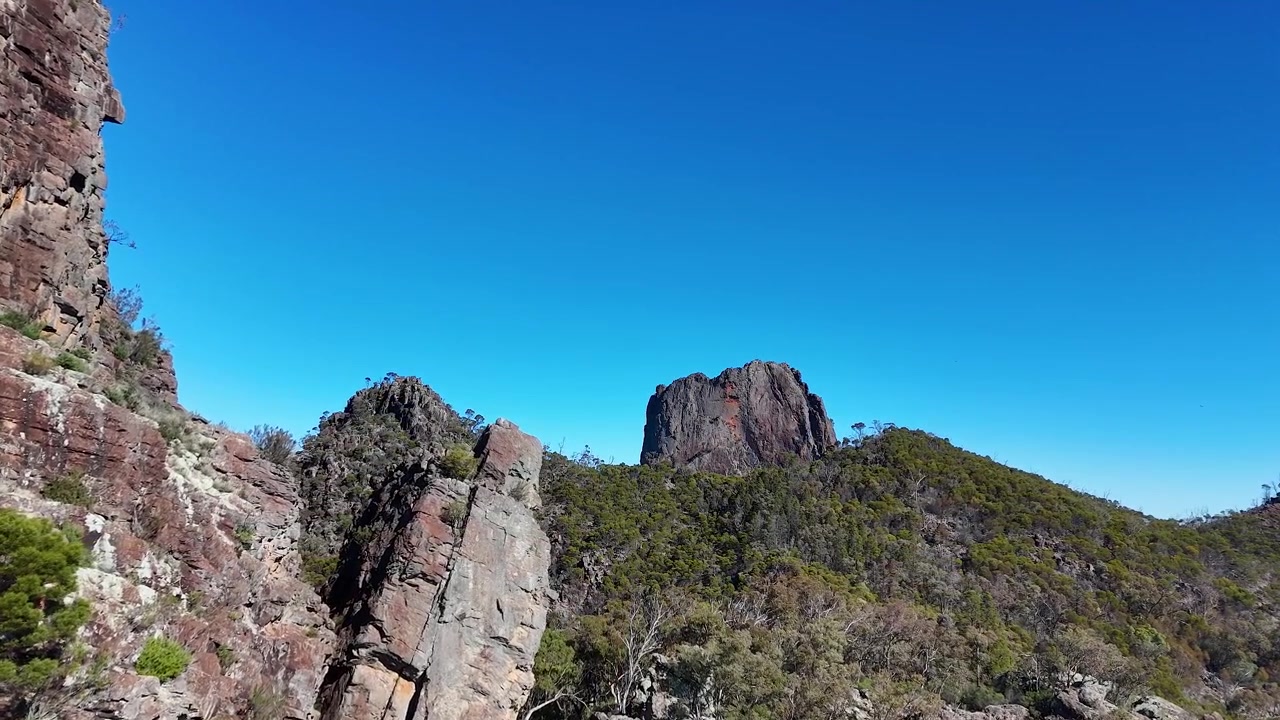 Ampia ripresa aerea con drone di guglie di roccia vulcanica e montagne sotto un cielo azzurro limpido.