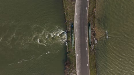 Luftaufnahme-Aus-Der-Vogelperspektive-Von-Hochwasser,-Das-Durch-Einen-Durchlass-Unter-Einer-Straße-Fließt,-Während-Schwere-Regenfälle-Große-Teile-Europas-Heimsuchen