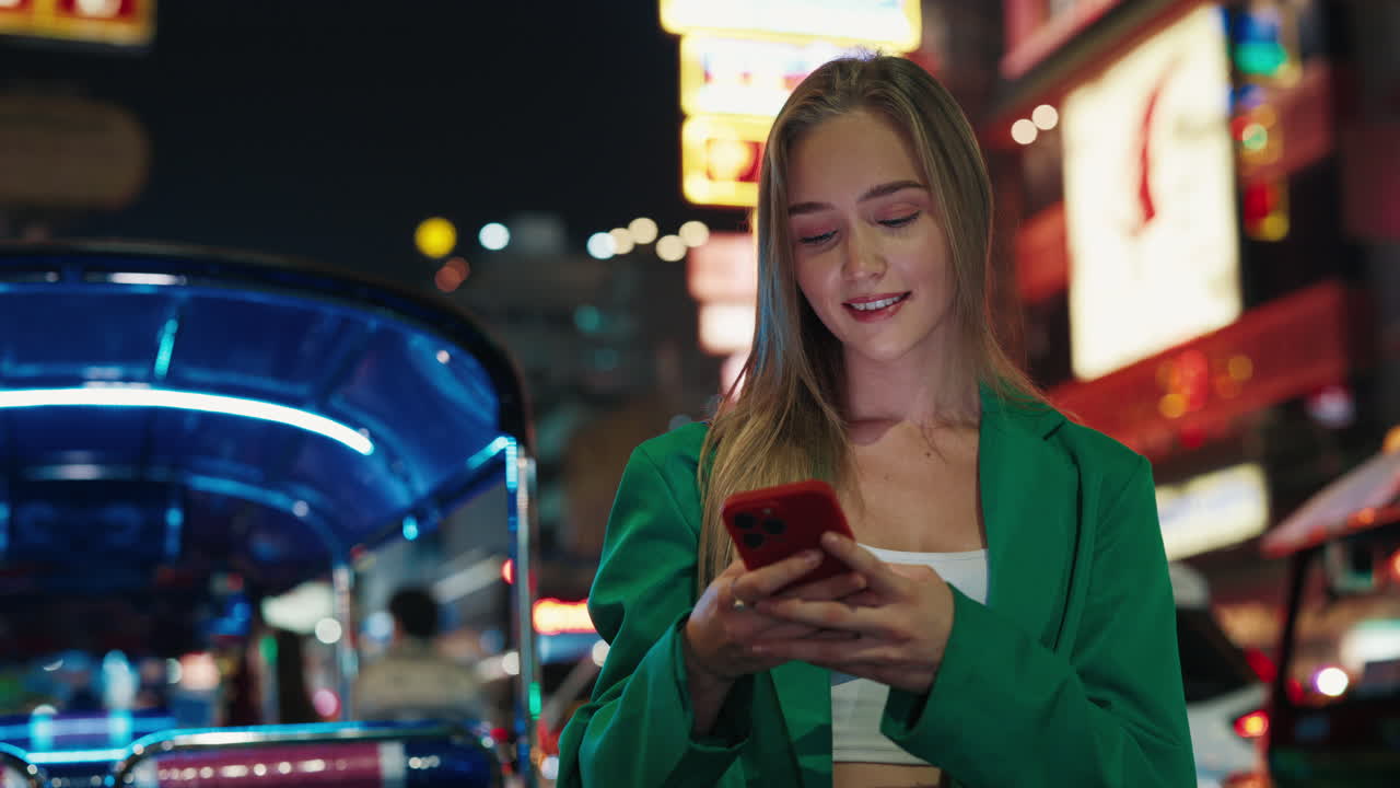 Young woman using phone at night market