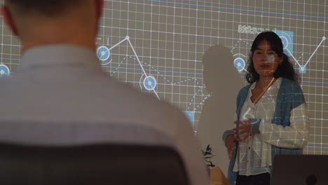 maestra dando lecciones de matemáticas o ciencias en una universidad o universidad de pie en la parte delantera de la clase con la proyección del gráfico 2