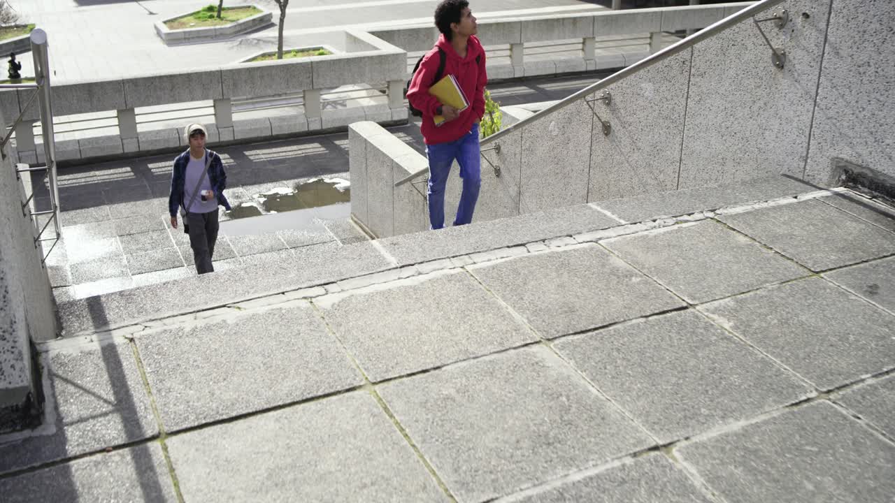 Amici studenti di diverse etnie camminano verso le scale della piazza, poi salgono portando quaderni e zaino.