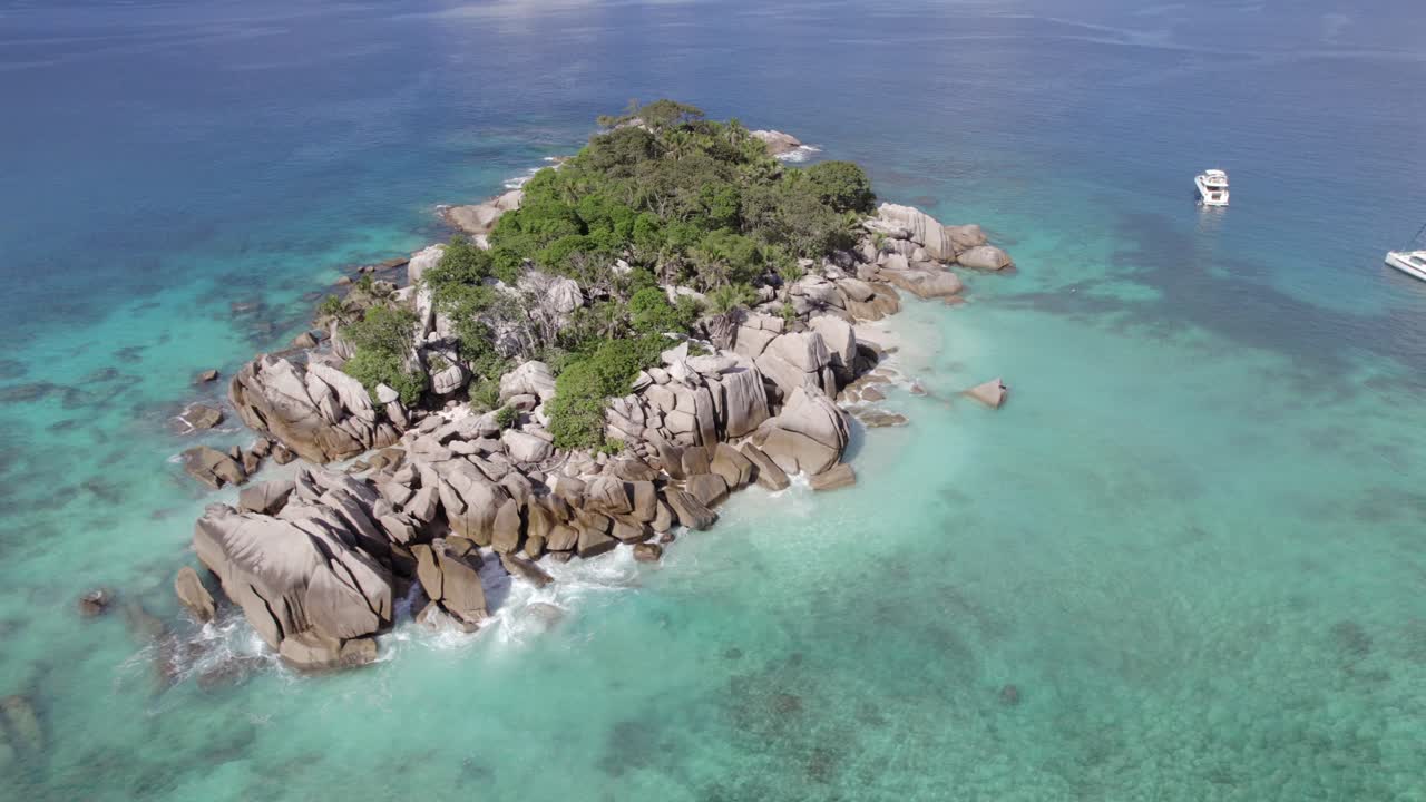 Ripresa aerea rotante dell'isola di Cocos, catamarano ormeggiato e yacht e barca di lusso, natura lussureggiante e incontaminata, pietre di granito, acqua turchese limpida, Seychelles 003 30fps
