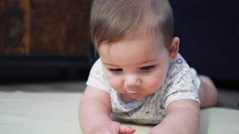 bebé sonriendo en el suelo mientras está en su estómago aprendiendo a arrastrarse