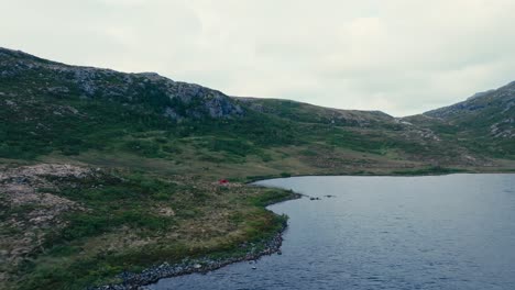 A-Red-Tent-Pitched-on-Pålvatnet-Lake's-Shore-in-Åfjord,-Trøndelag-County,-Norway---Aerial-Pullback-Shot