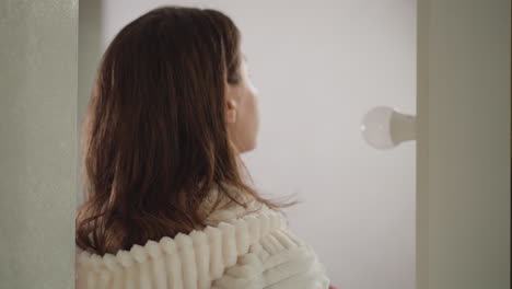 여자는 거울을 따라 복도를 따라 니다. 매력적인 여성은 샤워 후 스폰지로 피부를 보습하기 위해 화장품을 즐기는 아름다움의 날을 가지고 있습니다.