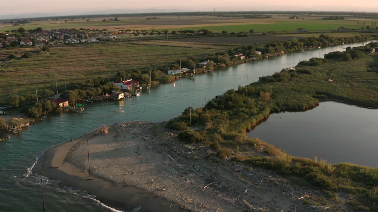 Ripresa aerea delle valli vicino a Ravenna dove il fiume sfocia nel mare con le tipiche capanne dei pescatori