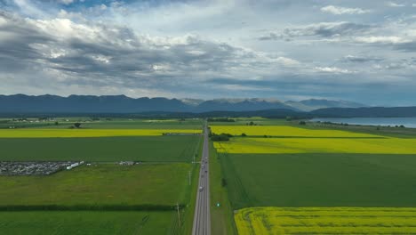 Scenic-Road-In-Canola-Fields-With-Cars-Traveling-From-Kalispell-Towards-Bigfork-In-Montana