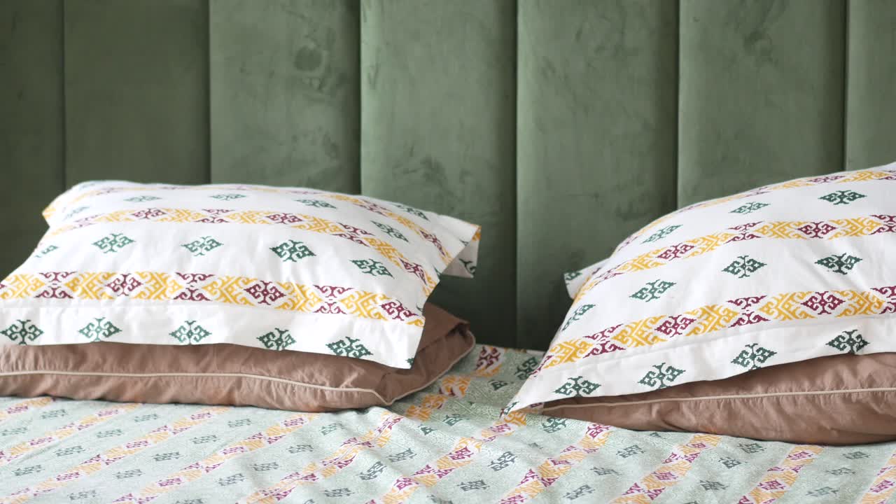 Bedroom with patterned pillows and a green headboard