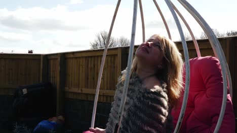 attractive woman relaxing and daydreaming in garden chair swing medium slow motion