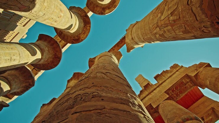 Vista radiale verso l'alto di colonne scolpite e soffitto dipinto al Tempio di Karnak.