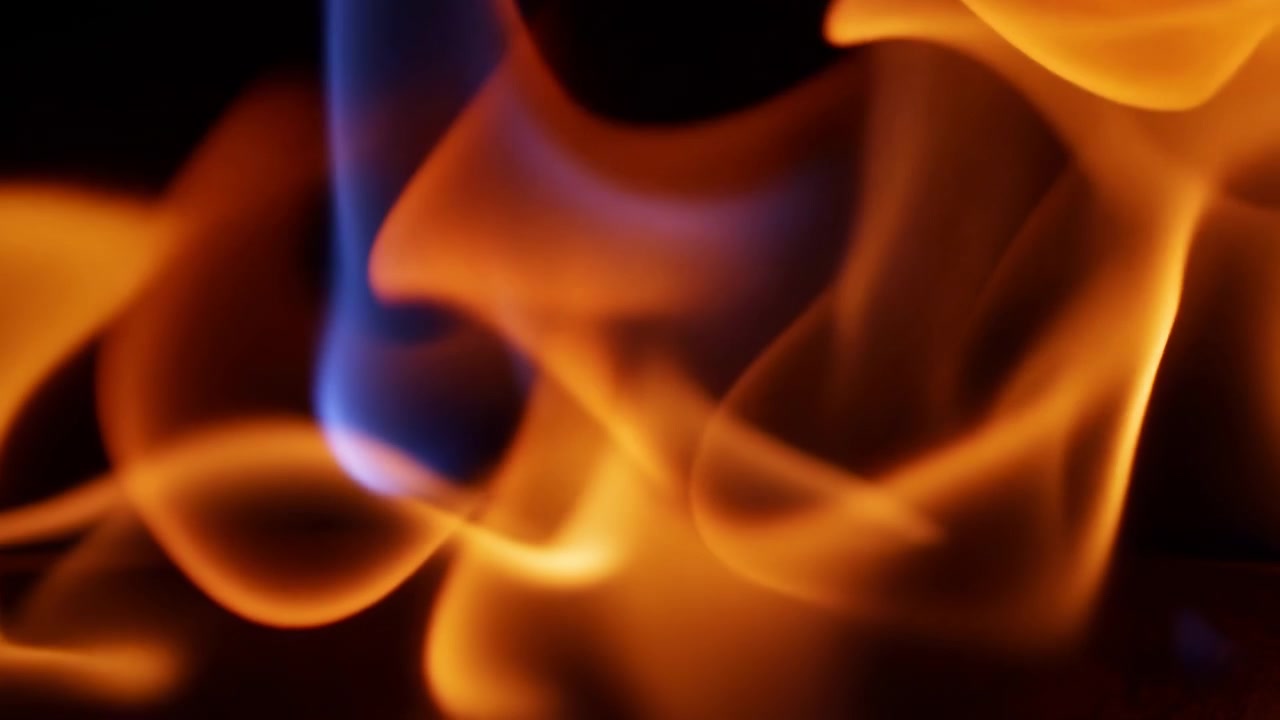 Abstract close view of orange and blue flame ribbons against dark background, with soft blur, layered curves, bright glow, deep shadow, and flowing heat that creates dramatic contrast, energetic mood