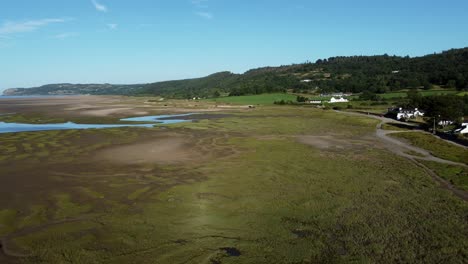 Aerial-reversing-view-Traeth-Coch-scenic-salt-marsh-moorland-countryside-erosion-at-sunset