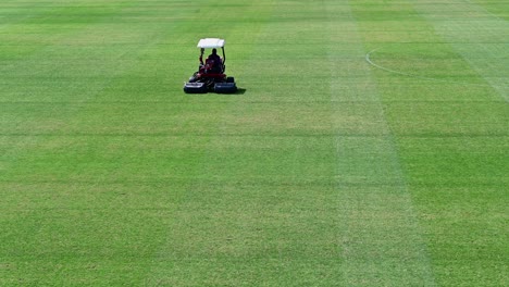 imágenes de 4k: un personal en un vehículo para cortar césped prepara un campo deportivo en un día soleado de verano en dubai, emiratos árabes unidos