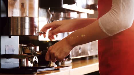 mid section of waitress holding portafilter filled with ground coffee